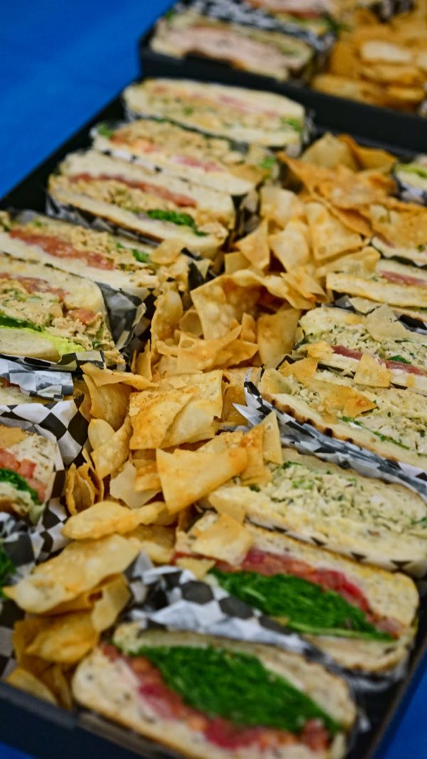 Taste of Splendour's sandwich platter: fresh bread piled high with greens and sliced meats, with a heap of crispy chips alongside.