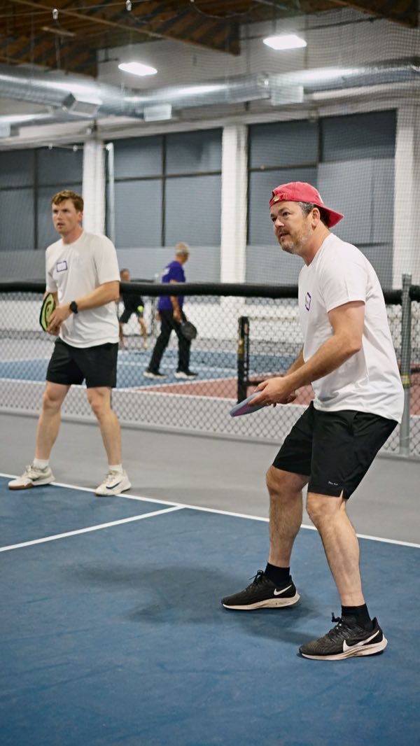 A player in a backwards cap moves in for the shot while a partner covers behind.
