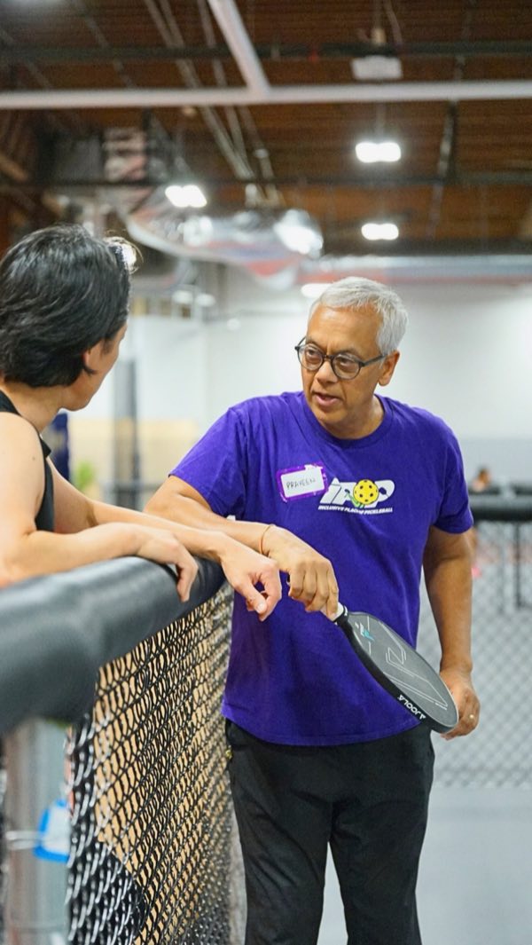 Co-founder Praveen Varshney leaning on the rail between games, deep in conversation, paddle in hand.