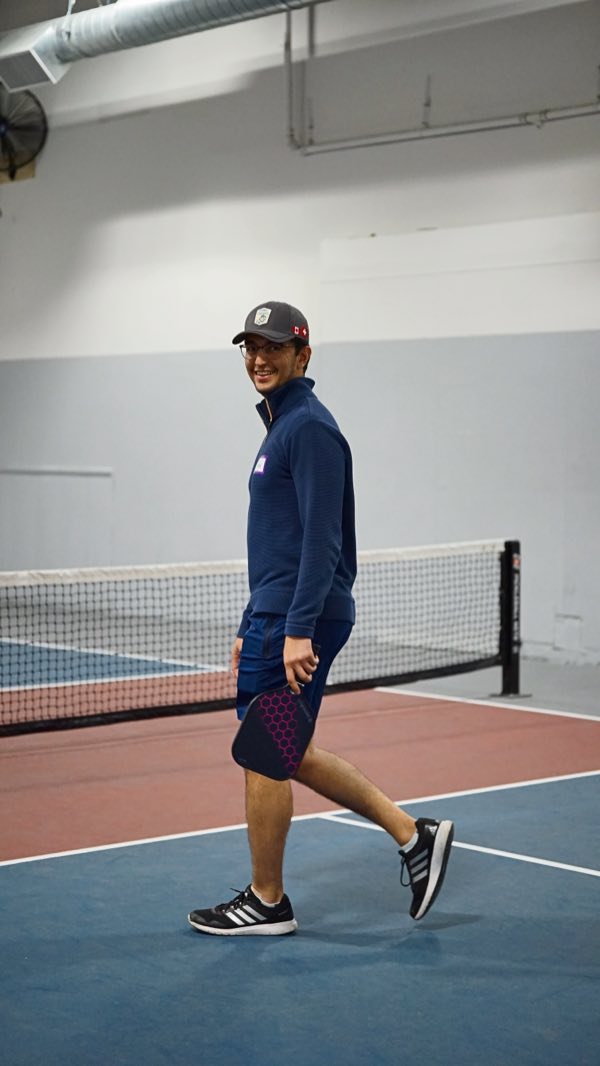 Walking back to his spot with a big grin for someone just out of frame.