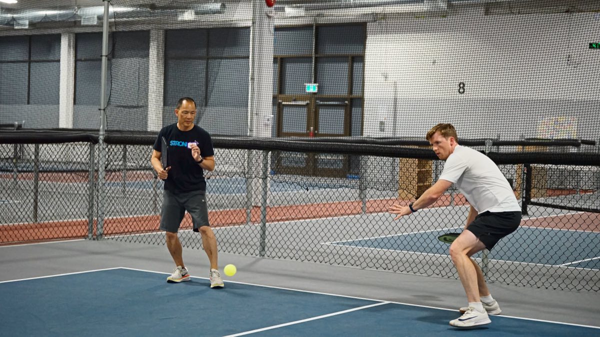 Mid-rally, both players down low and locked on a ball that's barely off the court.
