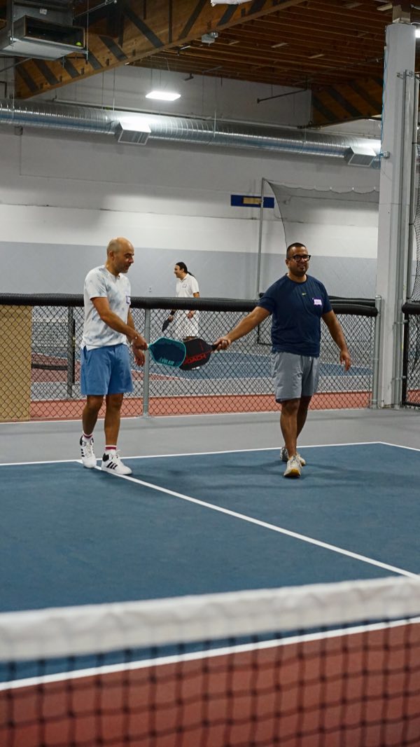 Partners meeting in the middle for a paddle tap after a good point.